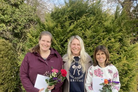 Erfreut nehmen Marjam Gues (links) und Jeanette Pfeifer (rechts) ein buntes Sträußchen zur Begrüßung entgegen. In der Mitte Kathrin Trackl, Leiterin im Waldkindergarten.