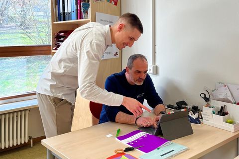 Rouven Rudisile (links, Abteilungsleitung Bildung, Familie und Kultur) und Thomas Toth (Einrichtungsleitung) testen das mobile Arbeiten in einem der Gruppenräume. An der Wand ist der neue, runde Access Point zu sehen, der dies ermöglicht.