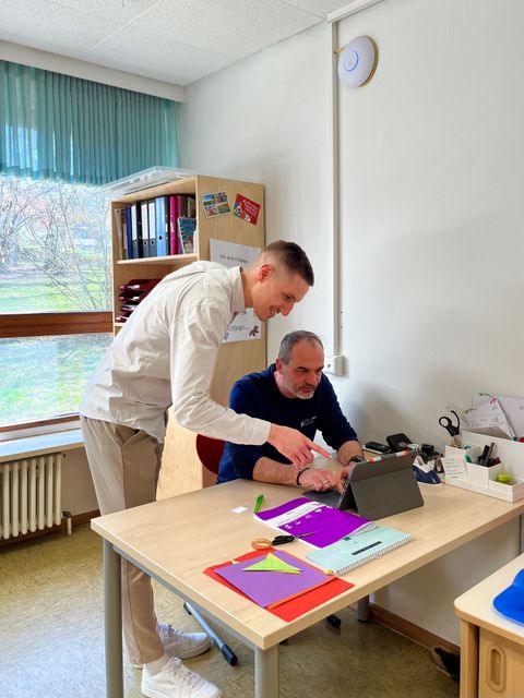 Rouven Rudisile (links, Abteilungsleitung Bildung, Familie und Kultur) und Thomas Toth (Einrichtungsleitung) testen das mobile Arbeiten in einem der Gruppenräume. An der Wand ist der neue, runde Access Point zu sehen, der dies ermöglicht.