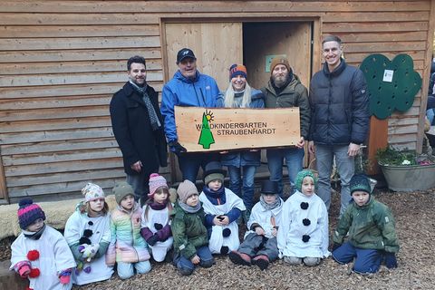 Übergabe des neuen Holzschildes. Es ist eine Arbeit von Felix Haberbusch, dessen Kinder den Waldkindergarten ebenfalls besuchen.