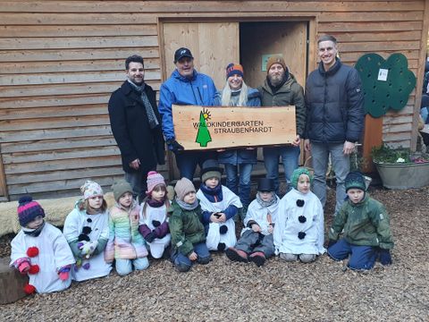 Übergabe des neuen Holzschildes. Es ist eine Arbeit von Felix Haberbusch, dessen Kinder den Waldkindergarten ebenfalls besuchen.